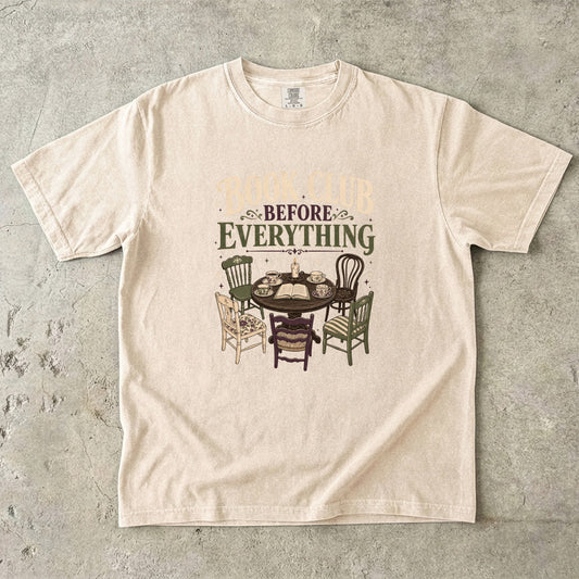 Ivory book club T-shirt featuring Book Club Before Everything with a vintage table, open book, teacups, candle and mismatched chairs.
