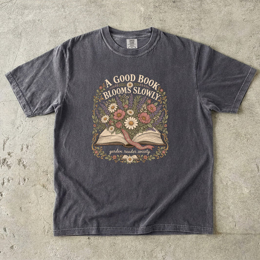 A Good Book Blooms Slowly botanical reading T-shirt with an open book and flowers on Pepper.