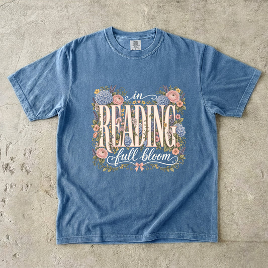 Blue Jean Comfort Colors reading T-shirt featuring the floral In Reading, Full Bloom book lover design with pink and blue flowers.