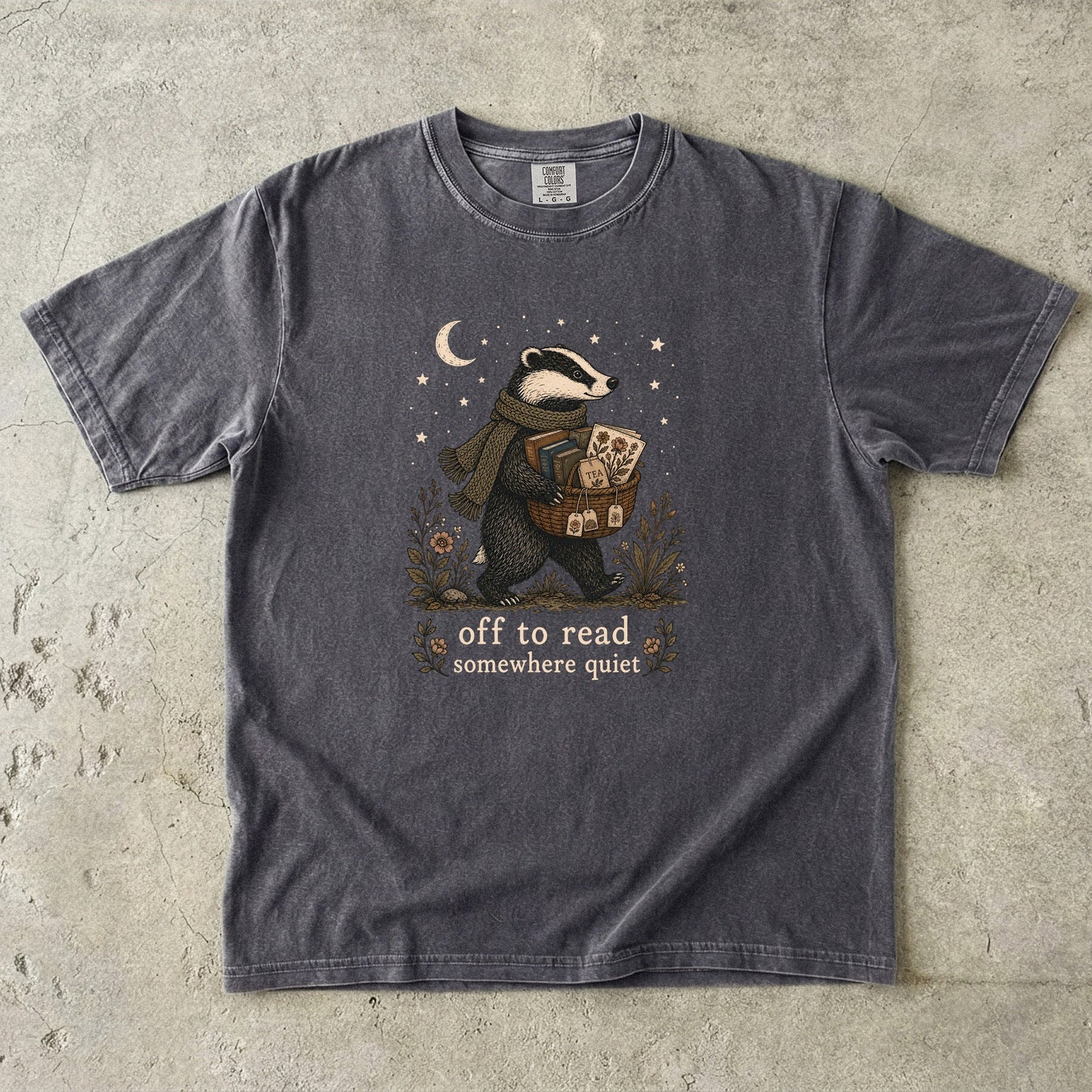 Off to Read Somewhere Quiet badger reading T-shirt in Pepper featuring a scarfed badger carrying books and tea