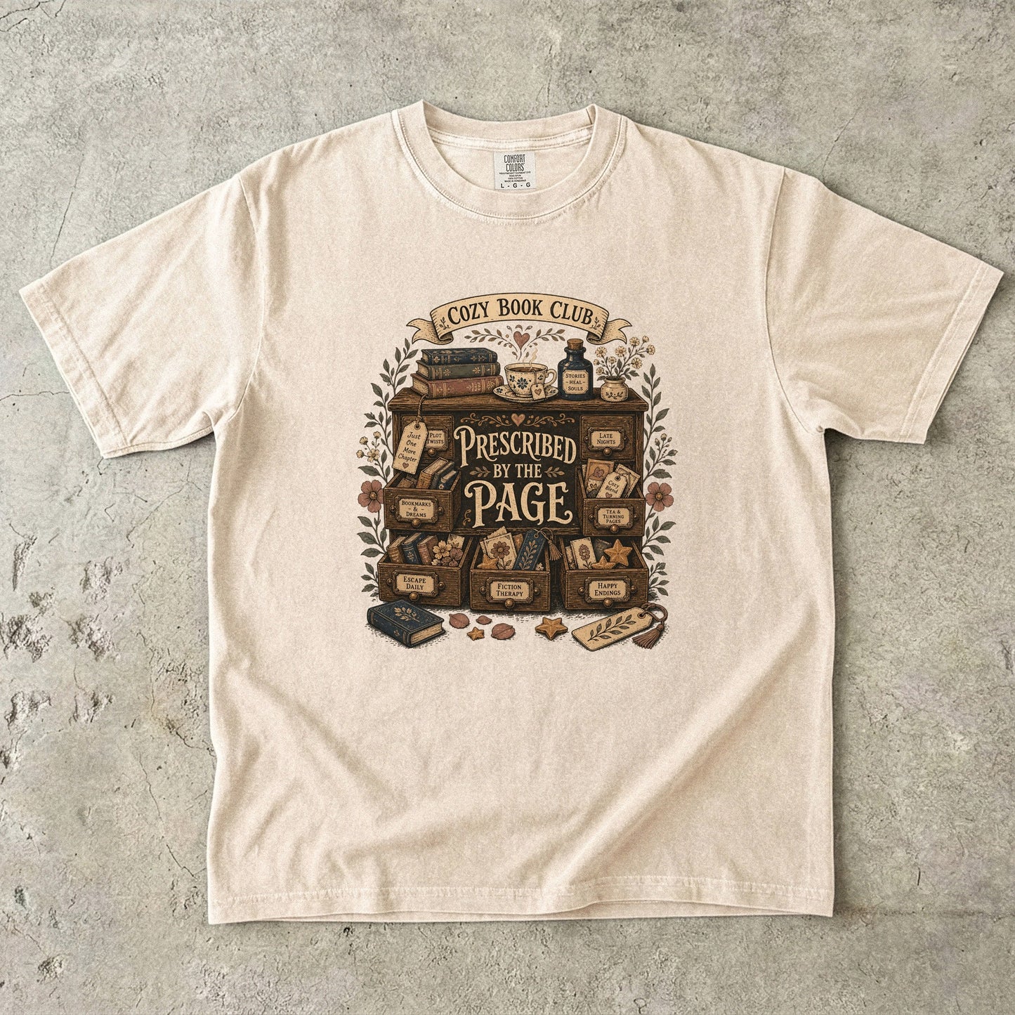 Prescribed by the Page cozy book club T-shirt in Ivory featuring a vintage literary cabinet filled with books, tea and reading-themed drawers