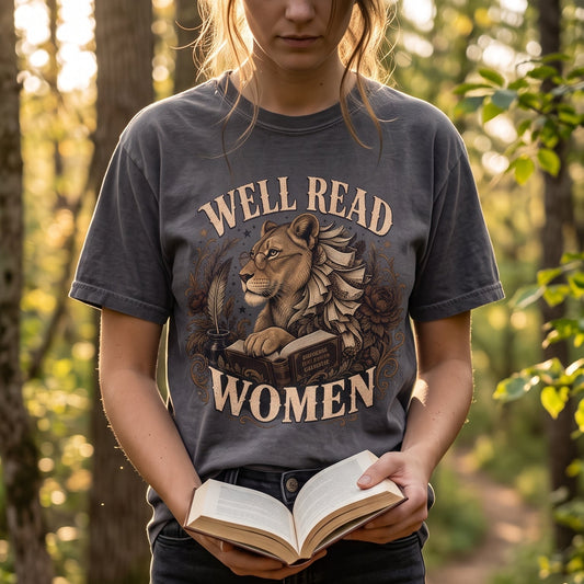 Woman reading outdoors wearing a Well Read Women book lover T-shirt with vintage lioness artwork.