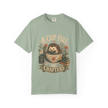 Front view of the A Cup Full of Chapters Book Lover Shirt on a Comfort Colors 1717 garment-dyed T-shirt in Bay featuring a cosy hedgehog, books and tea-inspired artwork.