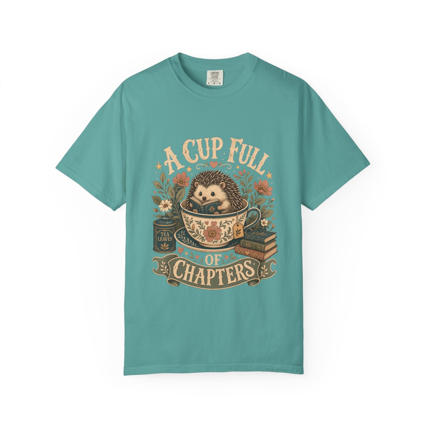 Front view of the A Cup Full of Chapters Book Lover Shirt on a Comfort Colors 1717 garment-dyed T-shirt in Seafoam featuring a vintage hedgehog reading illustration.
