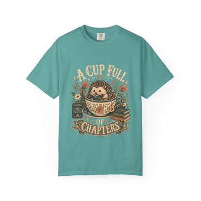 Front view of the A Cup Full of Chapters Book Lover Shirt on a Comfort Colors 1717 garment-dyed T-shirt in Seafoam featuring a vintage hedgehog reading illustration.