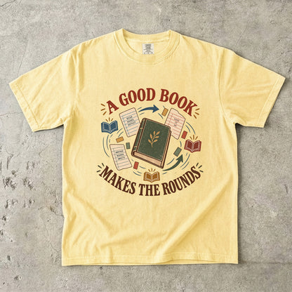Butter book lover T-shirt with “A Good Book Makes the Rounds,” a book, arrows and sharing notes
