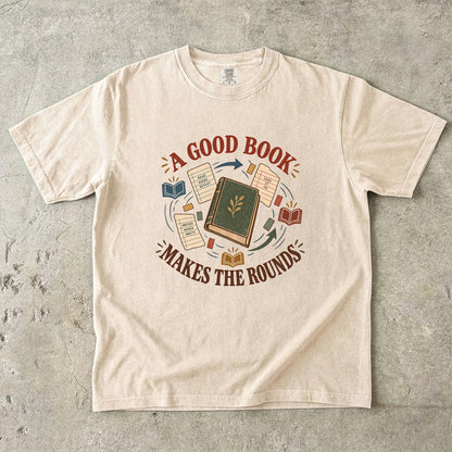 Ivory book lover T-shirt with “A Good Book Makes the Rounds,” a book, arrows and sharing notes