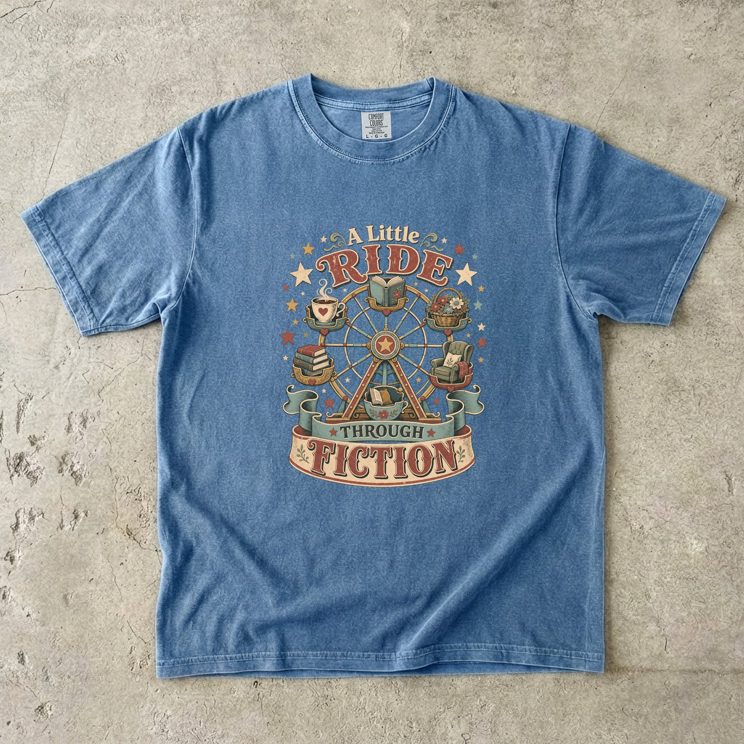 Front view of a Blue Jean Comfort Colors book lover T-shirt featuring the vintage "A Little Ride Through Fiction" illustration with books, tea, reading chair and Ferris wheel.