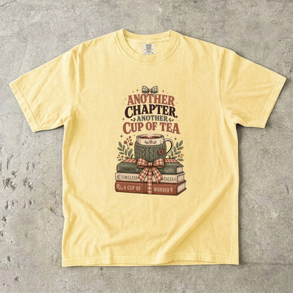 Another Chapter Another Cup of Tea reading shirt in Butter featuring a warm teacup and nostalgic book stack illustration.