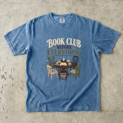 Blue Jean book club T-shirt featuring Book Club Before Everything with a vintage table, open book, teacups, candle and mismatched chairs.