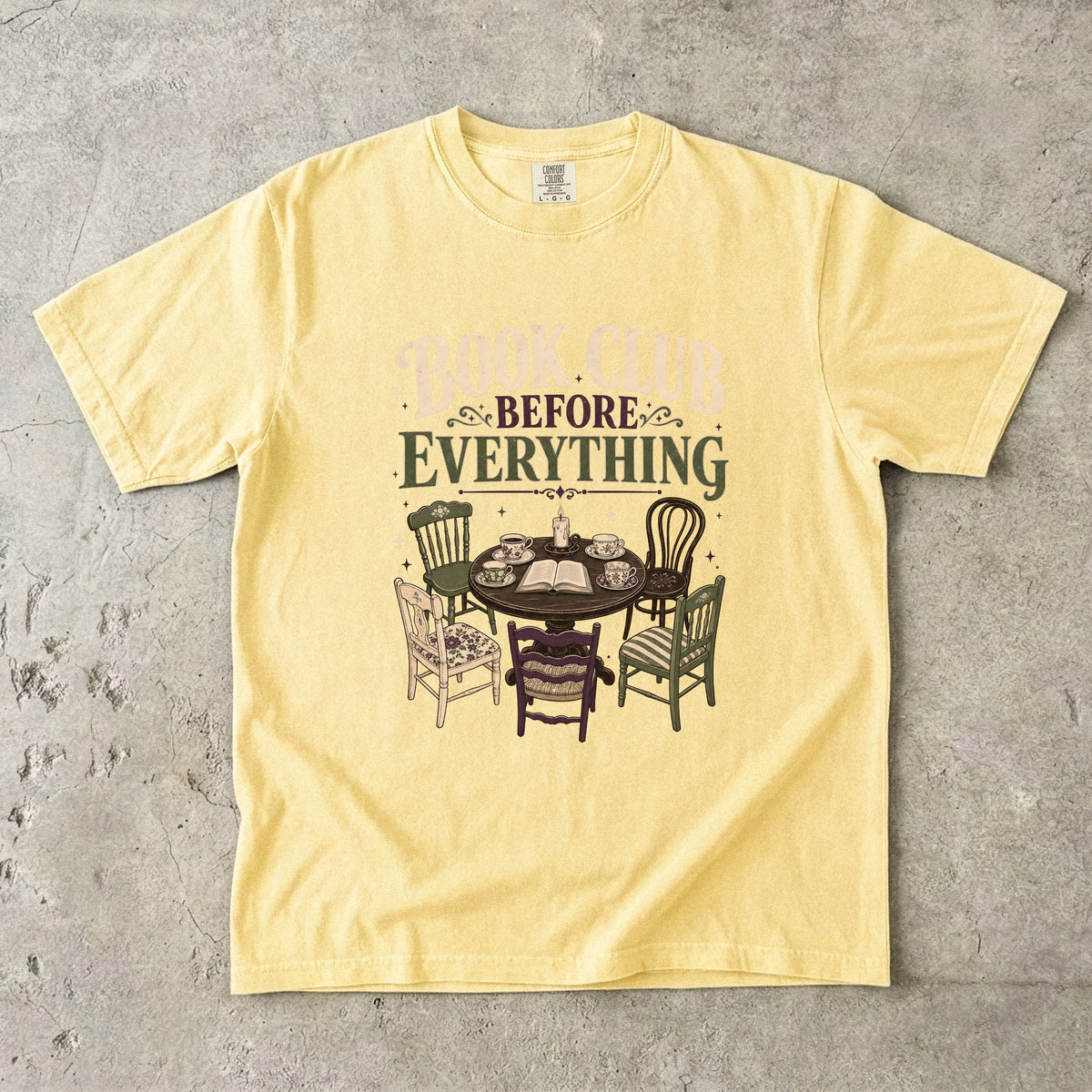 Butter book club T-shirt featuring Book Club Before Everything with a vintage table, open book, teacups, candle and mismatched chairs.