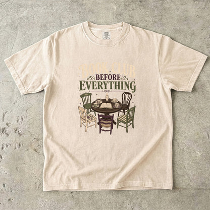 Ivory book club T-shirt featuring Book Club Before Everything with a vintage table, open book, teacups, candle and mismatched chairs.