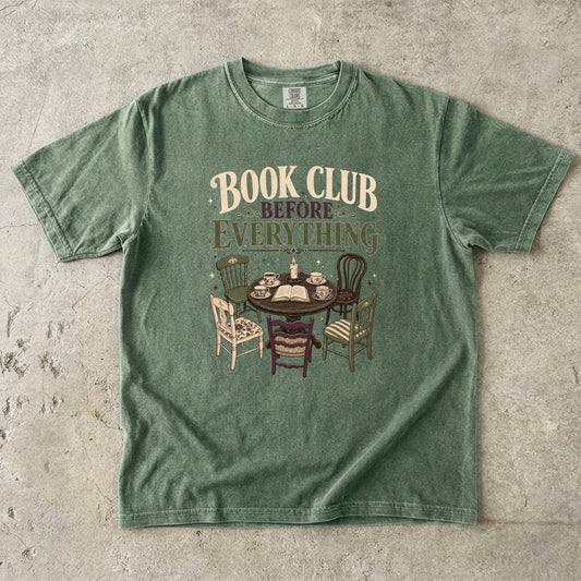 Moss book club T-shirt featuring Book Club Before Everything with a vintage table, open book, teacups, candle and mismatched chairs.