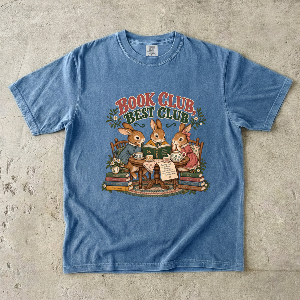 Blue Jean T-shirt featuring “Book Club, Best Club” with three rabbits reading together at a tea table, floral china, books and daisies.