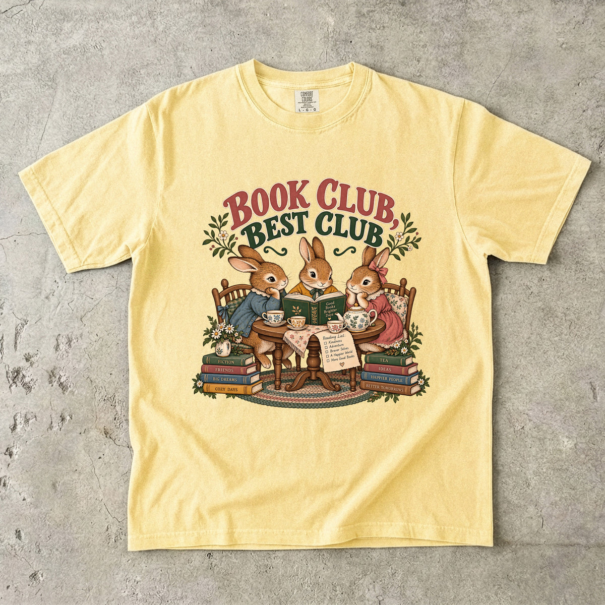 Butter T-shirt featuring “Book Club, Best Club” with three rabbits reading together at a tea table, floral china, books and daisies.