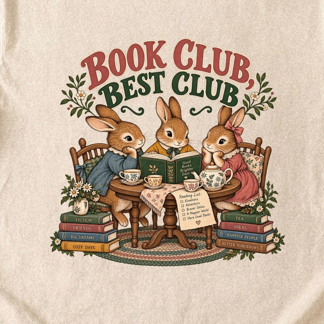 Close-up of the “Book Club, Best Club” T-shirt design, showing three rabbits reading together at a tea table, floral china, books and daisies.