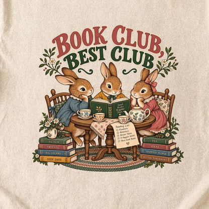 Close-up of the “Book Club, Best Club” T-shirt design, showing three rabbits reading together at a tea table, floral china, books and daisies.