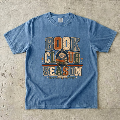 Blue Jean Comfort Colors Book Club Season T-shirt featuring vintage collegiate lettering, stacked books and a teacup.