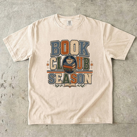 Ivory Comfort Colors Book Club Season T-shirt with retro varsity lettering, books and a cozy cup of tea.