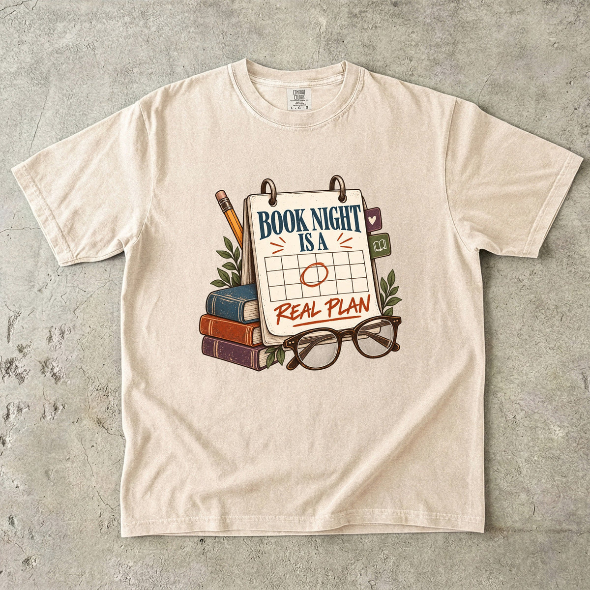 Ivory reading T-shirt with “Book Night Is a Real Plan” on a marked calendar beside books and glasses