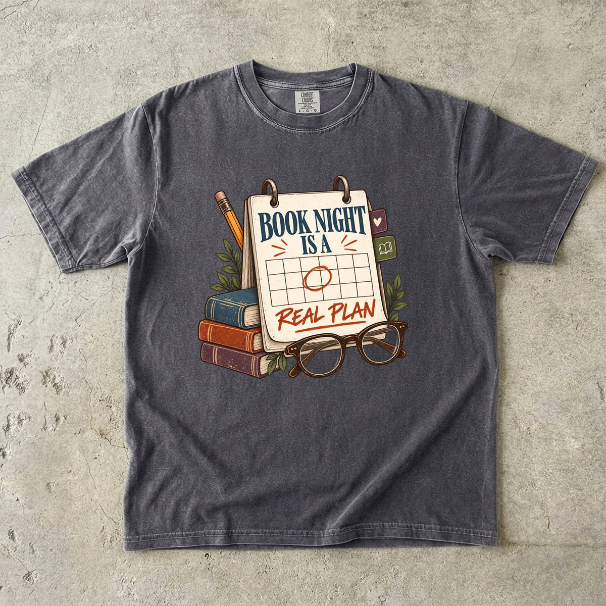 Pepper reading T-shirt with “Book Night Is a Real Plan” on a marked calendar beside books and glasses