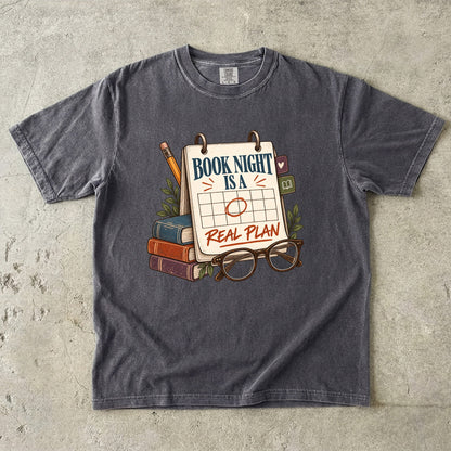 Pepper reading T-shirt with “Book Night Is a Real Plan” on a marked calendar beside books and glasses