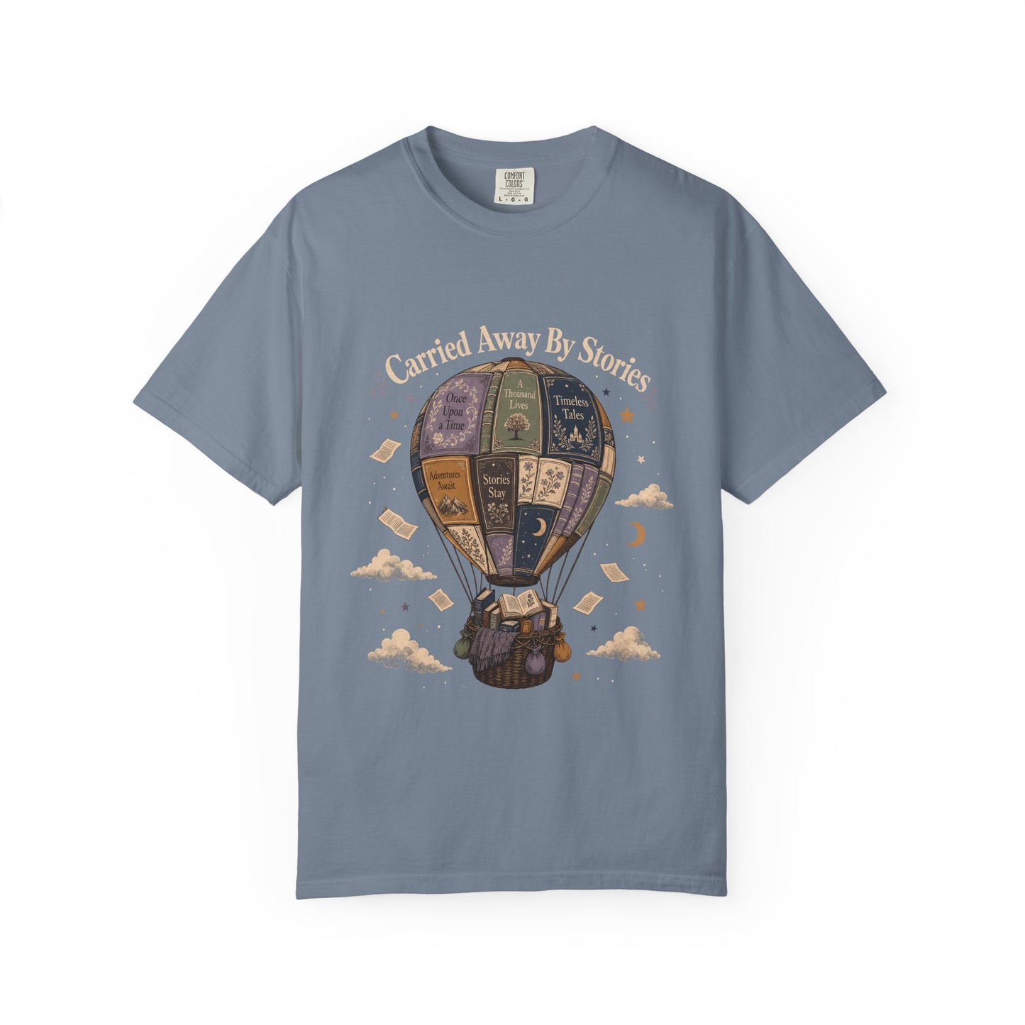 Front view of the Carried Away By Stories book lover shirt on a Blue Jean Comfort Colors 1717 T-shirt featuring a vintage hot air balloon made from illustrated books and the phrase "Carried Away By Stories."