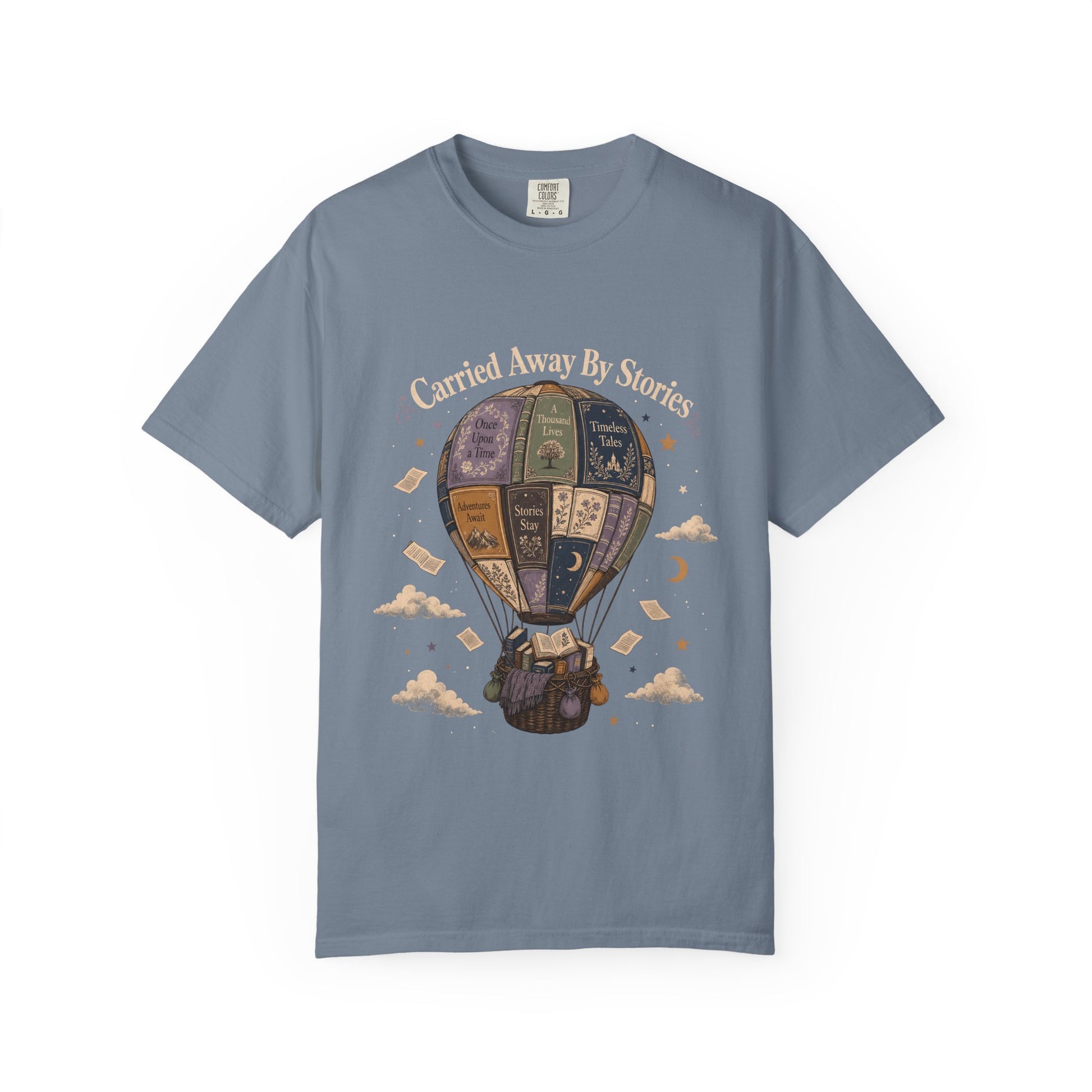 Front view of the Carried Away By Stories book lover shirt on a Blue Jean Comfort Colors 1717 T-shirt featuring a vintage hot air balloon made from illustrated books and the phrase "Carried Away By Stories."