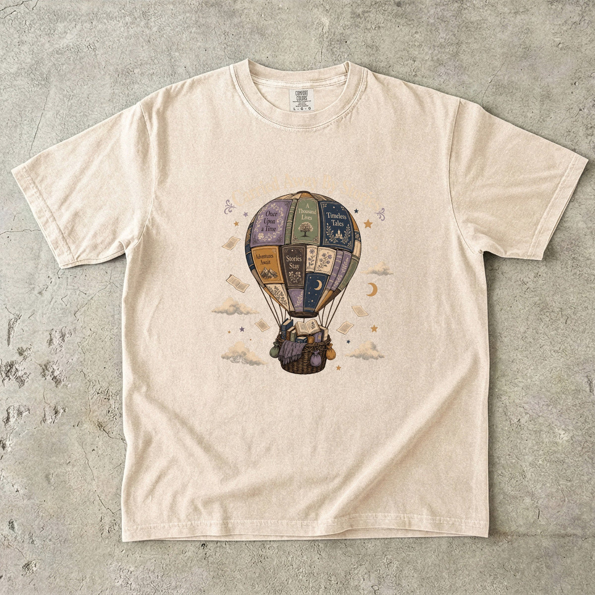 Carried Away by Stories book lover T-shirt in Ivory featuring a hot air balloon made from books with floating pages and clouds