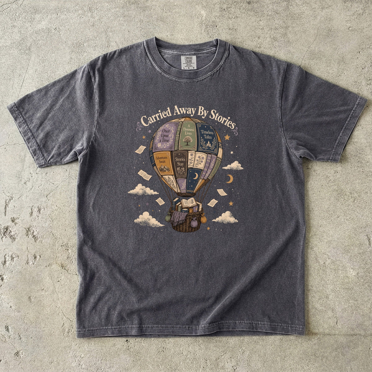 Carried Away by Stories book lover T-shirt in Pepper featuring a hot air balloon made from books with floating pages and clouds