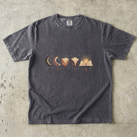 Pepper T-shirt with a horizontal arrangement of moon-shaped books, open books, tassels and a golden sun.