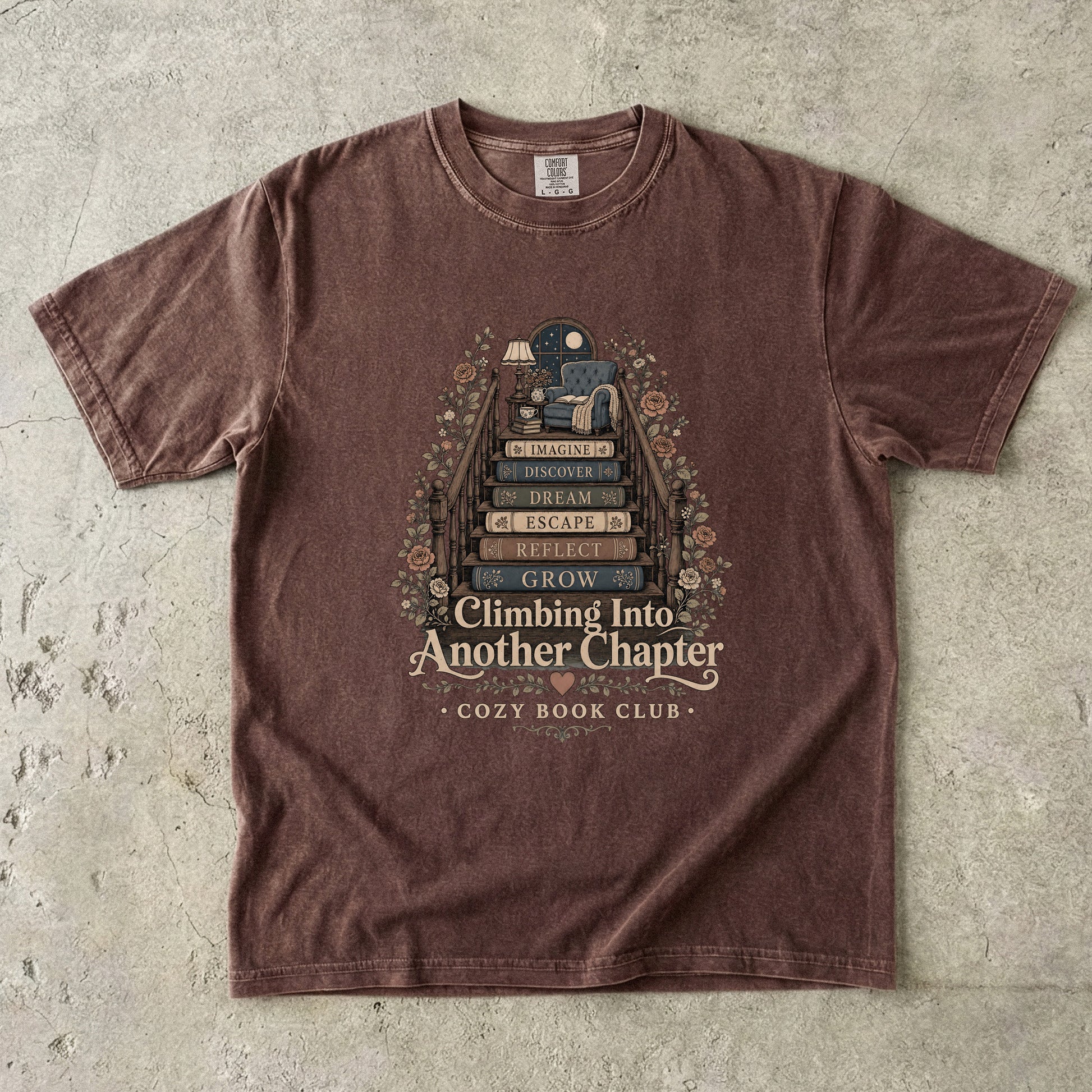 Front view of an Espresso Comfort Colors® book lover T-shirt featuring the Climbing Into Another Chapter vintage literary illustration with book stairs, flowers and a cozy reading nook.