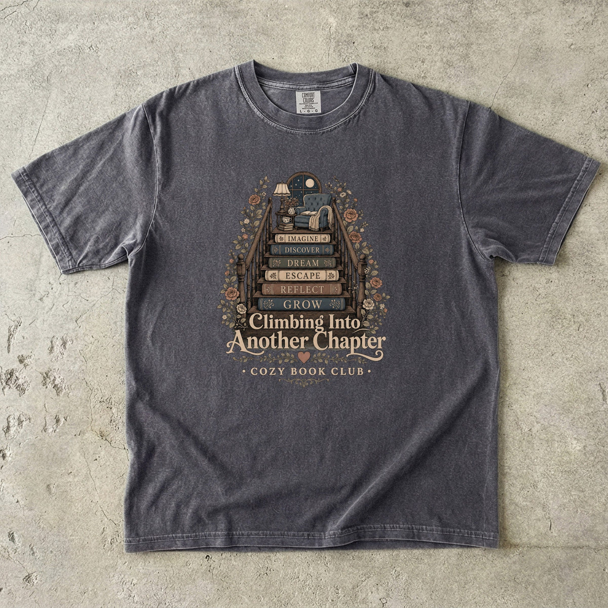 Climbing Into Another Chapter book lover T-shirt in Pepper featuring a staircase of books leading to a cozy reading chair