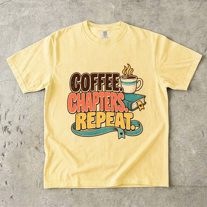 Butter T-shirt featuring “Coffee. Chapters. Repeat.” with brown, coral and gold lettering, a steaming mug, a teal book and heart-shaped bookmark details.