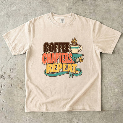 Ivory T-shirt featuring “Coffee. Chapters. Repeat.” with brown, coral and gold lettering, a steaming mug, a teal book and heart-shaped bookmark details.