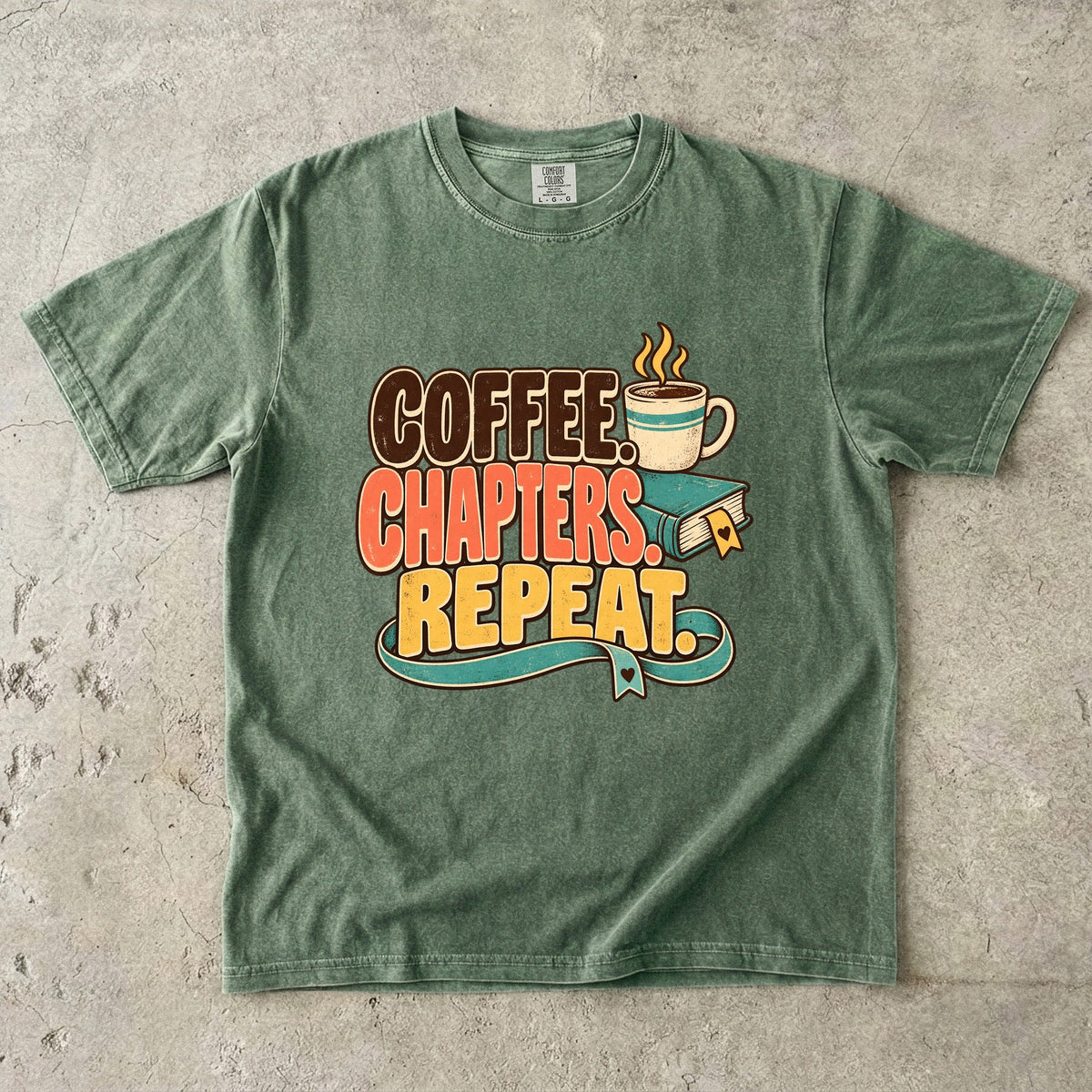 Moss T-shirt featuring “Coffee. Chapters. Repeat.” with brown, coral and gold lettering, a steaming mug, a teal book and heart-shaped bookmark details.