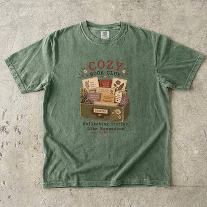 Cozy Book Club T-shirt in Moss featuring a vintage story collection with classic books, flowers and reading notes