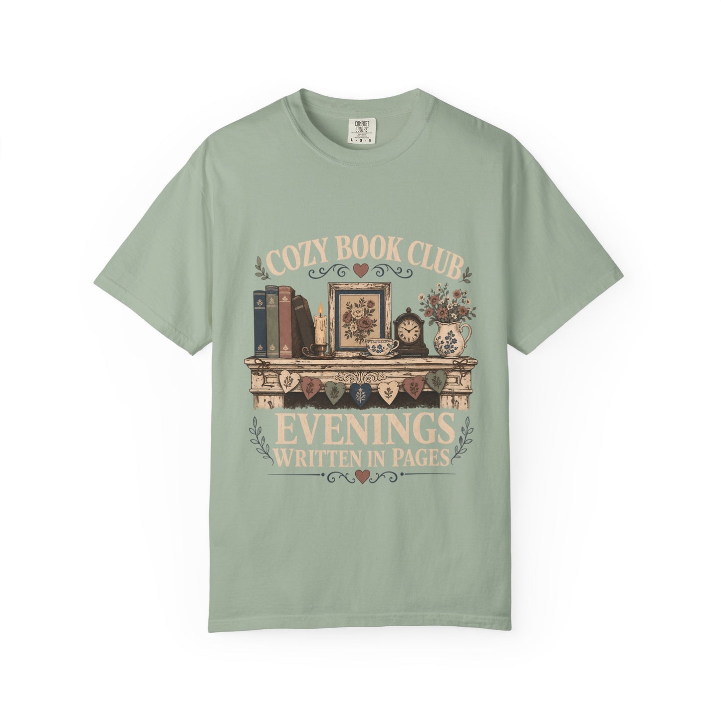 Front view of a Bay Comfort Colors® book club T-shirt featuring the "Cozy Book Club Evenings Written in Pages" vintage bookshelf, candle, teacup and floral mantel illustration.