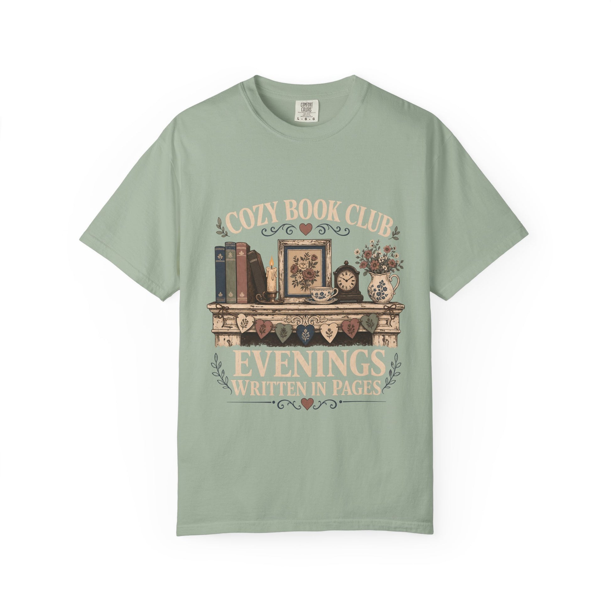 Front view of a Bay Comfort Colors® book club T-shirt featuring the "Cozy Book Club Evenings Written in Pages" vintage bookshelf, candle, teacup and floral mantel illustration.