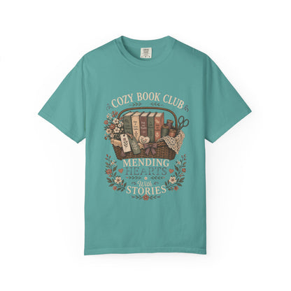 Cozy Book Club – Mending Hearts With Stories design printed on a Bay Comfort Colors 1717 T-shirt featuring a vintage basket of classic novels and floral accents.

