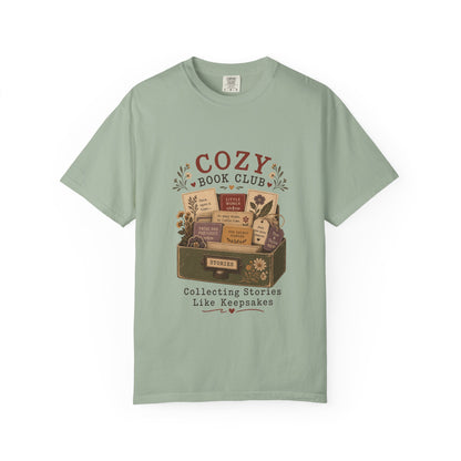 Front view of the Cozy Book Club Comfort Colors T-shirt in Bay featuring a vintage-inspired illustration of classic books in a library drawer.

