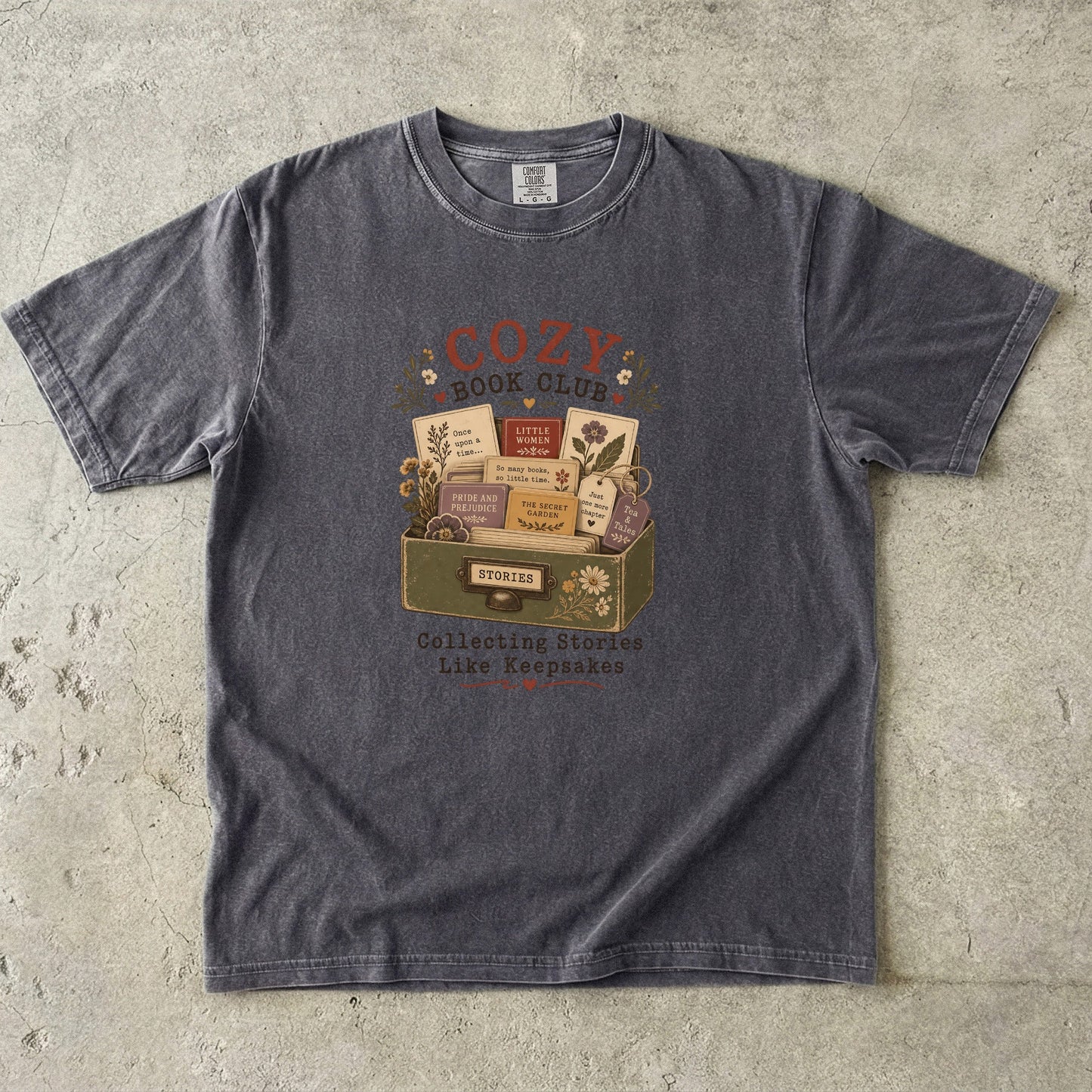 Front view of the Cozy Book Club Comfort Colors T-shirt in Pepper featuring a vintage book club illustration with classic novels and floral accents.


