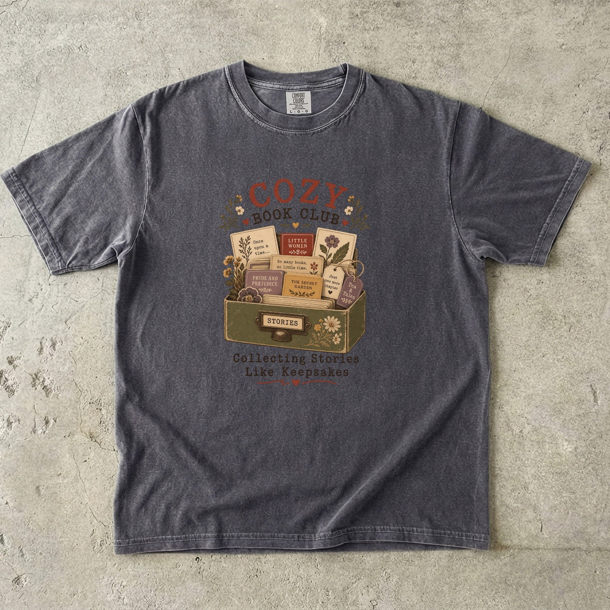 Front view of the Cozy Book Club Comfort Colors T-shirt in Pepper featuring a vintage book club illustration with classic novels and floral accents.

