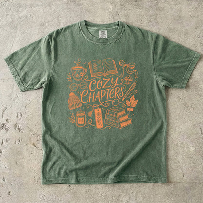 Moss Comfort Colors bookish T-shirt featuring the Cozy Chapters line art design with books and cozy reading essentials.