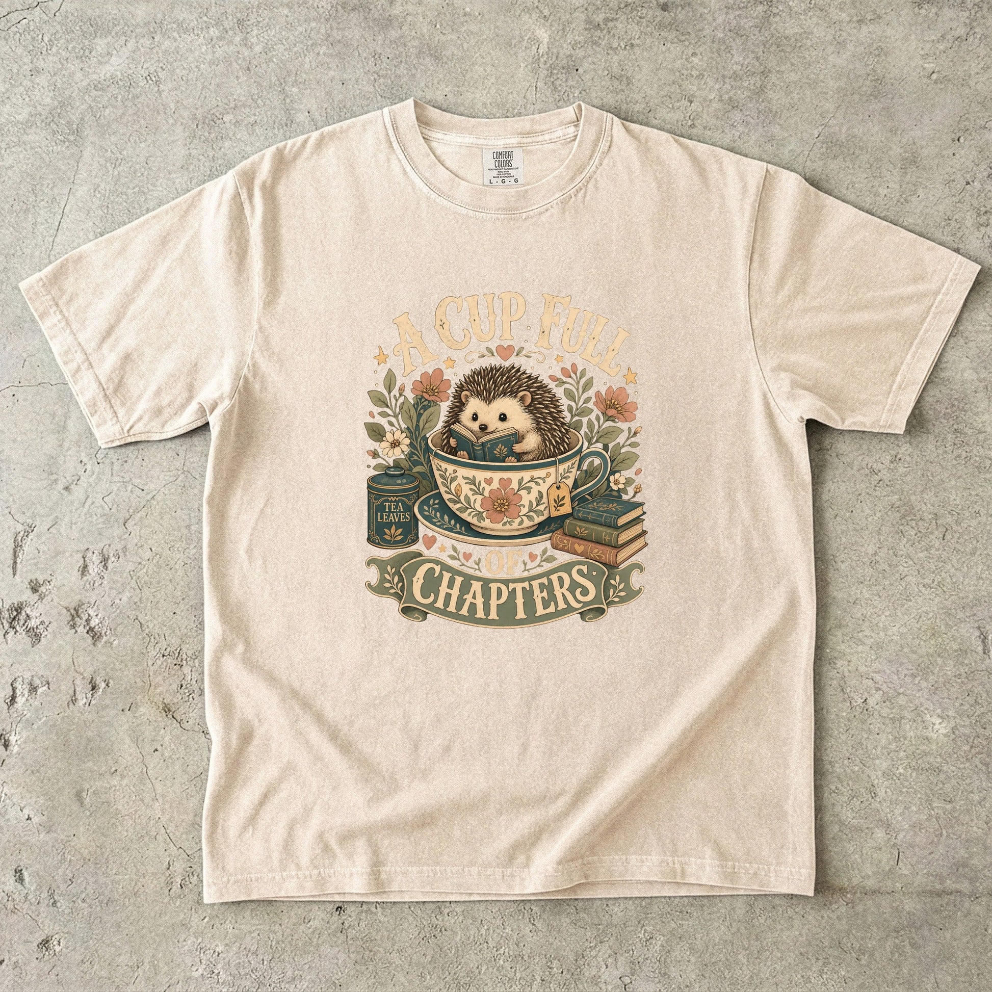 A Cup Full of Chapters hedgehog reading T-shirt in Ivory featuring a hedgehog reading inside a floral teacup with books