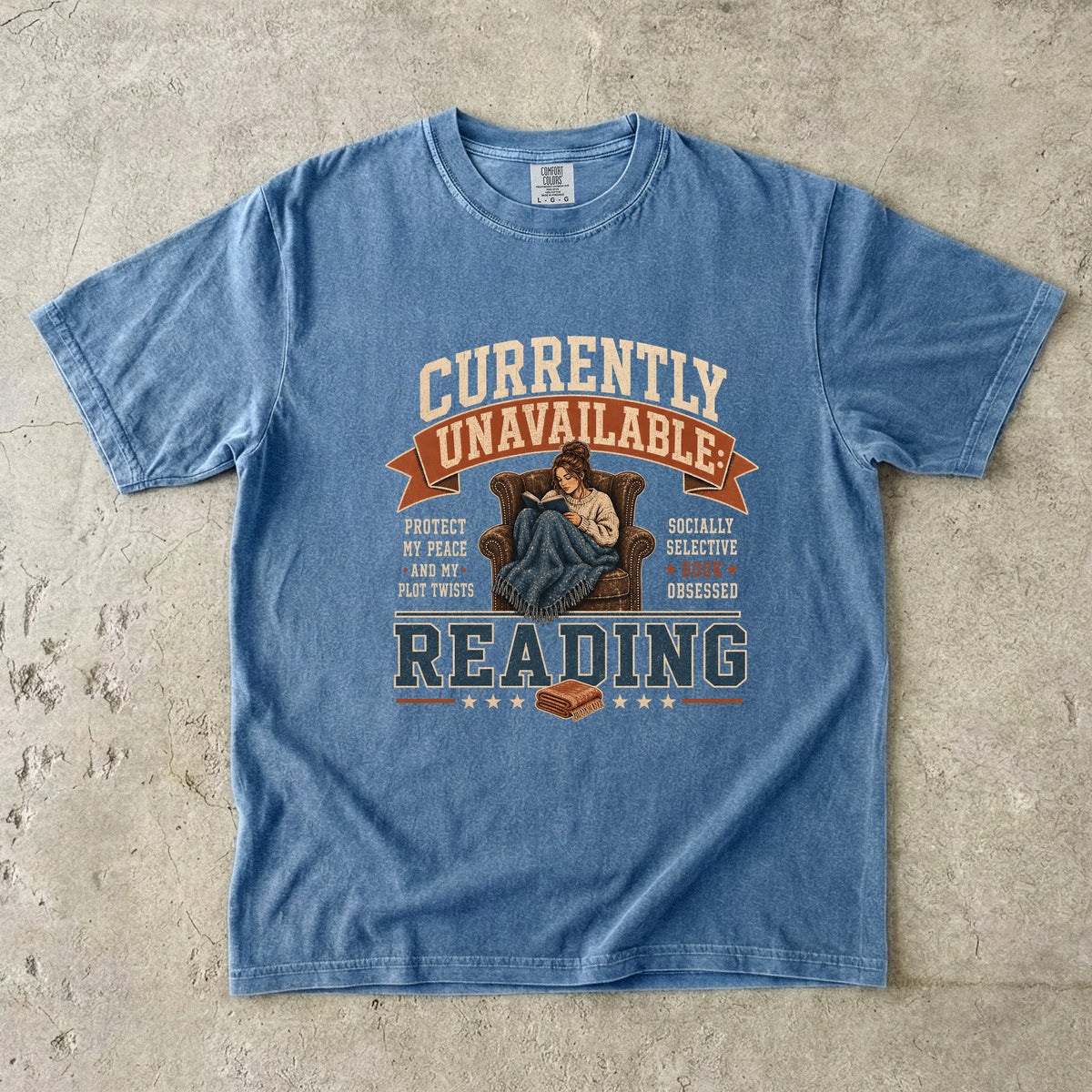 Blue Jean reading T-shirt featuring Currently Unavailable: Reading with a reader curled in a leather armchair beneath a blanket with a book.