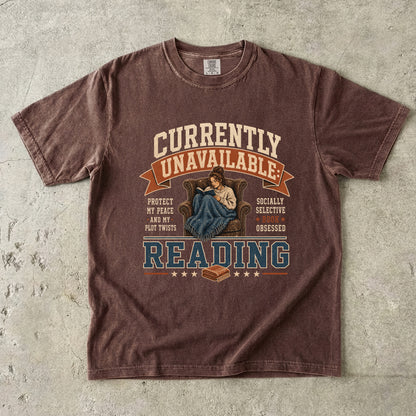 Espresso reading T-shirt featuring Currently Unavailable: Reading with a reader curled in a leather armchair beneath a blanket with a book.