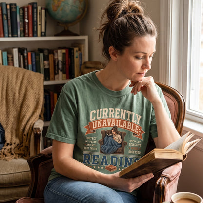 Currently Unavailable: Reading T-shirt featuring a book-obsessed reader curled in a leather armchair beneath a blanket.