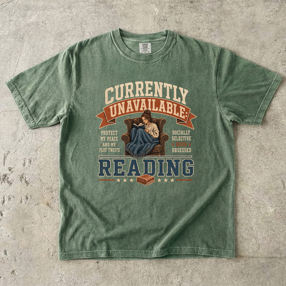 Moss reading T-shirt featuring Currently Unavailable: Reading with a reader curled in a leather armchair beneath a blanket with a book.