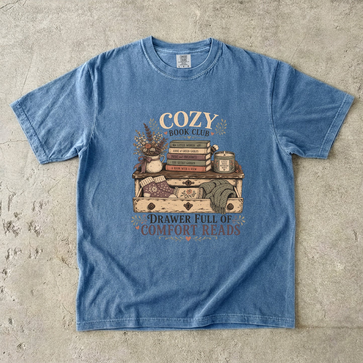 Drawer Full of Comfort Reads reading T-shirt in Blue Jean featuring stacked books, candle, flowers, knitted socks and blankets